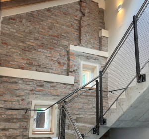 Fertiggestelltes Treppenhaus im Projekt Artist for Kids mit freigelegtem Sichtmauerwerk und Treppenaufgang mit Sichtbeton und Stahlgeländer